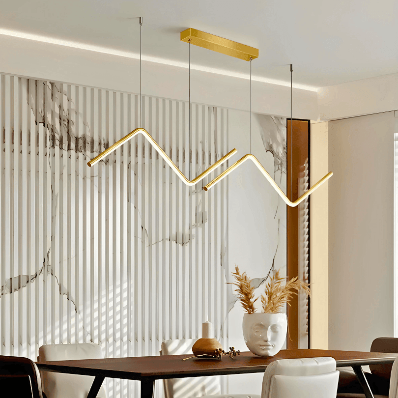Pendente linear dourado em zigue-zague aceso sobre mesa de jantar de madeira