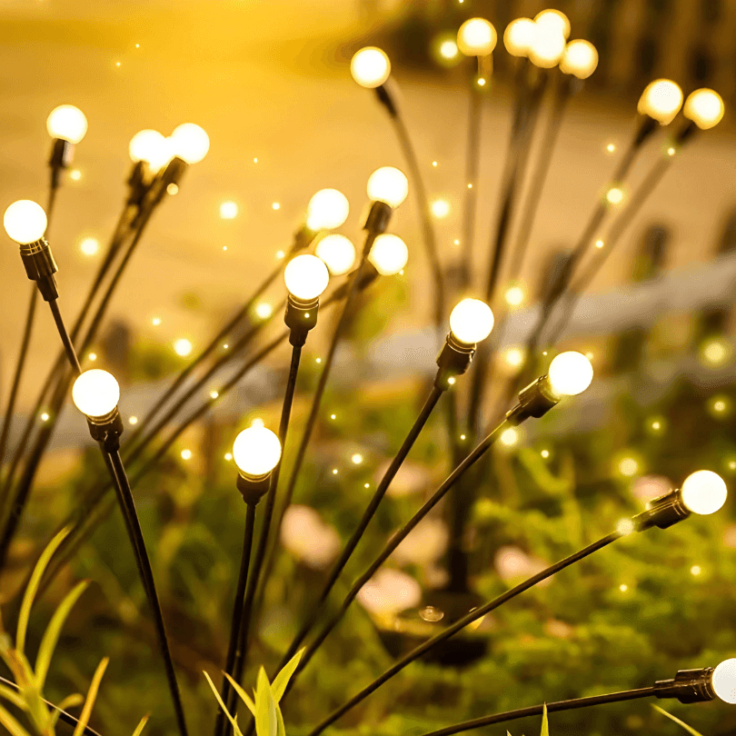 Esferas de luz branca quente na ponta das hastes finas, vistas de perto no jardim