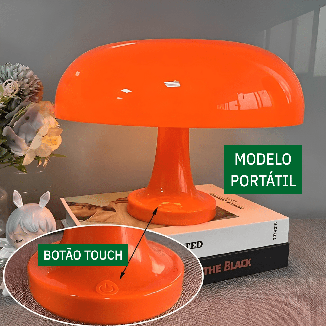 Luminária laranja sobre livros, com destaque para o botão touch na base
