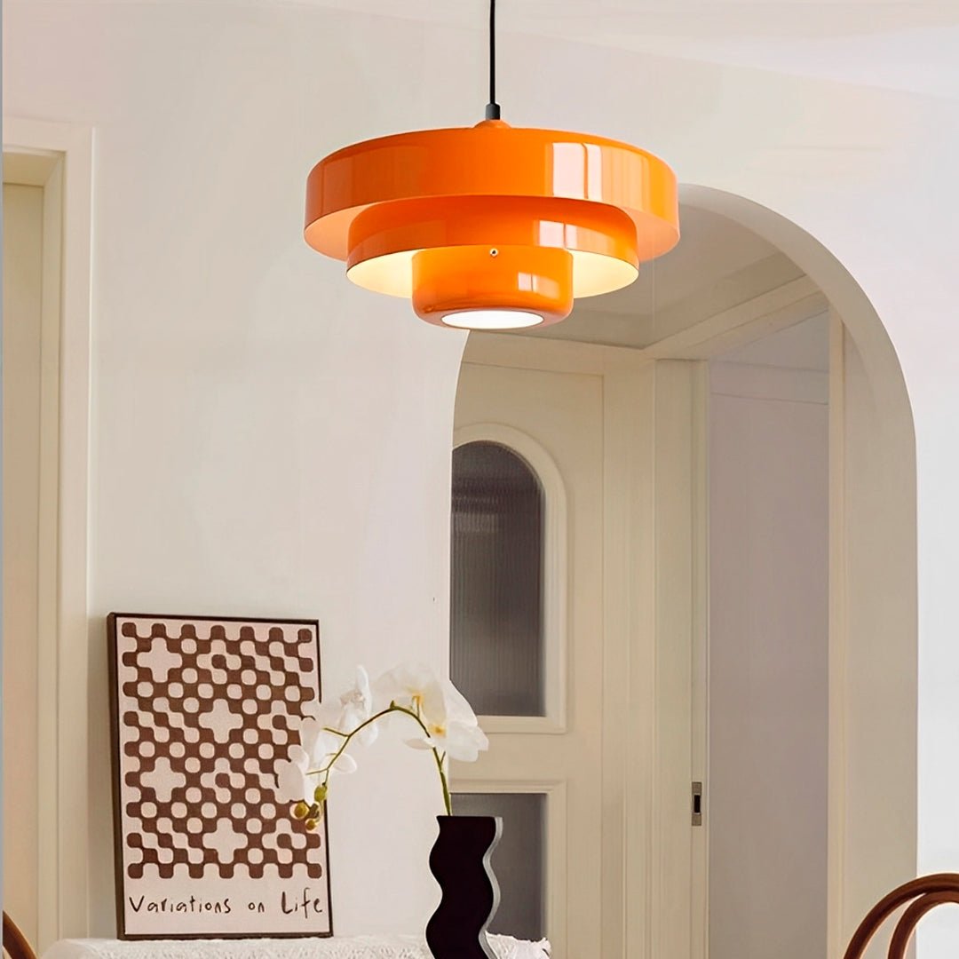 Pendente laranja aceso diante de um arco, com quadro e vaso de flores brancas embaixo