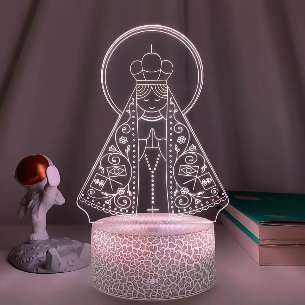 Nossa Senhora Aparecida em luz clara sobre base branca craquelada, ao lado de livros