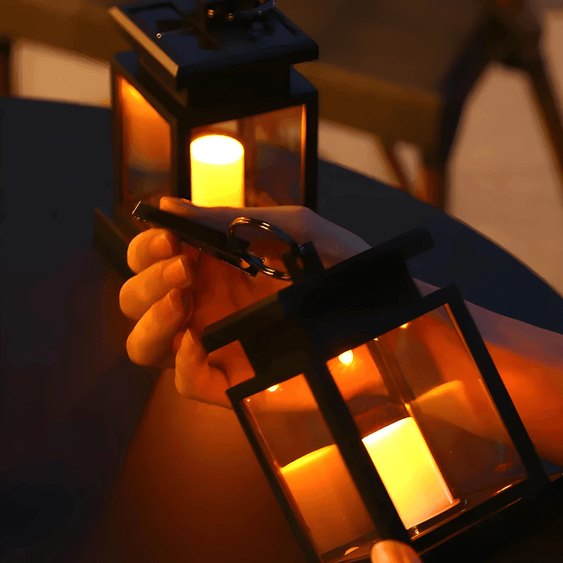 Mão segurando a lanterna pela presilha com argola, com vela de LED acesa ao fundo