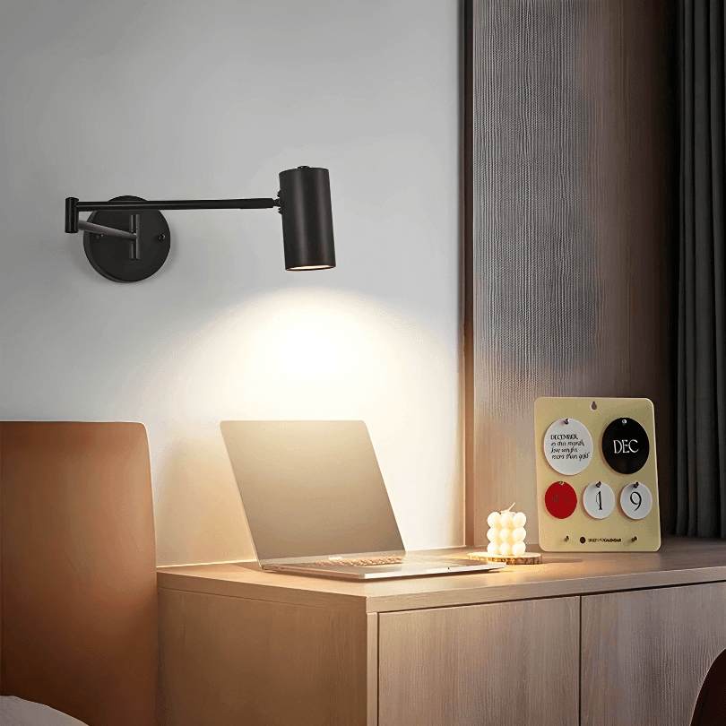 Arandela preta com a cúpula inclinada para baixo, iluminando um notebook na mesa