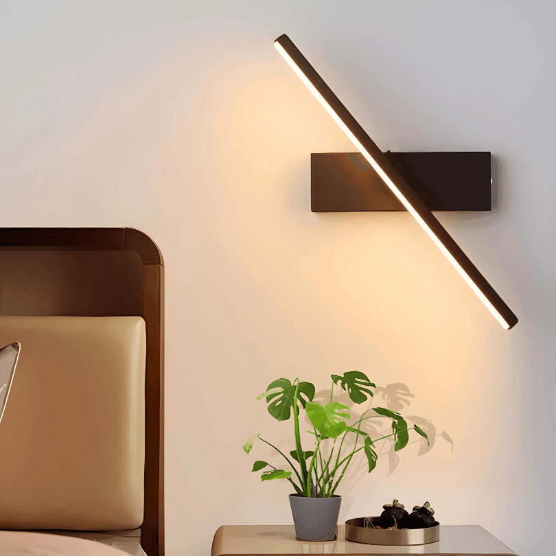 Arandela preta de LED na diagonal acesa em luz quente ao lado da cama