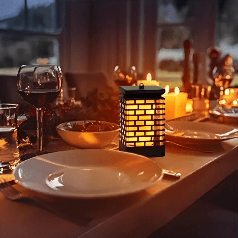 Lanterna acesa no centro de uma mesa de jantar posta, entre pratos, taças e velas
