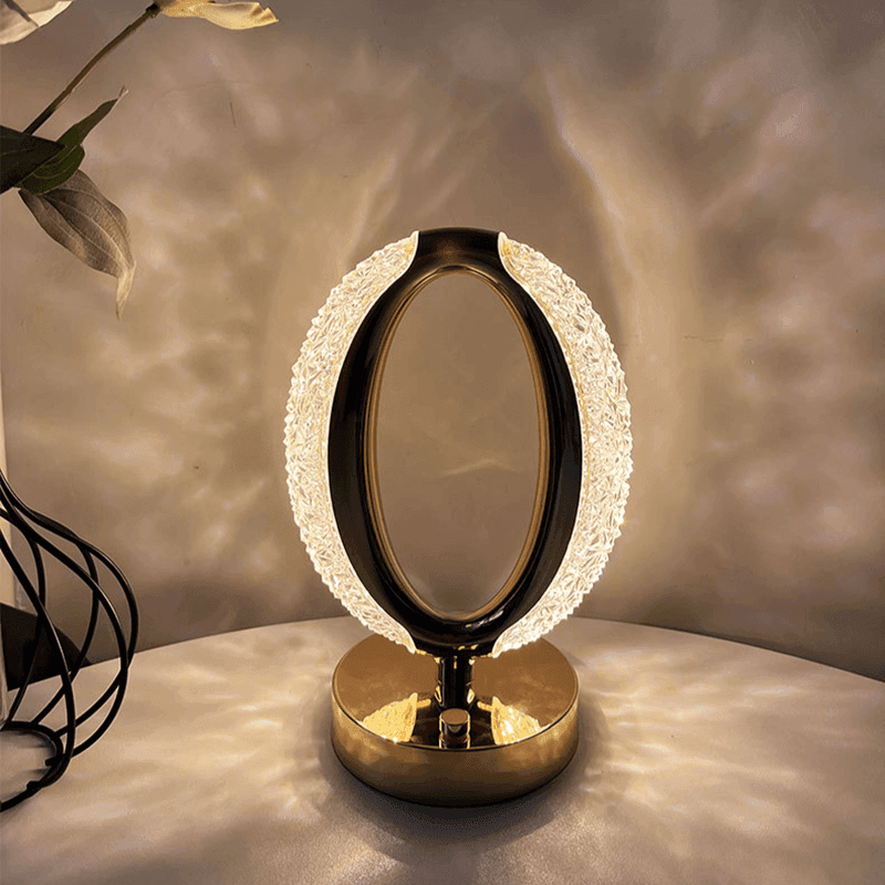 Luminária de anel acesa projetando pontos de luz sobre a parede e a mesa