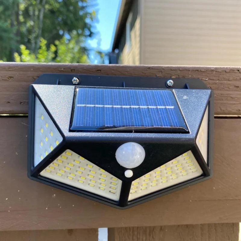 Luminária solar presa a uma cerca de madeira, com parafusos no topo e sensor central