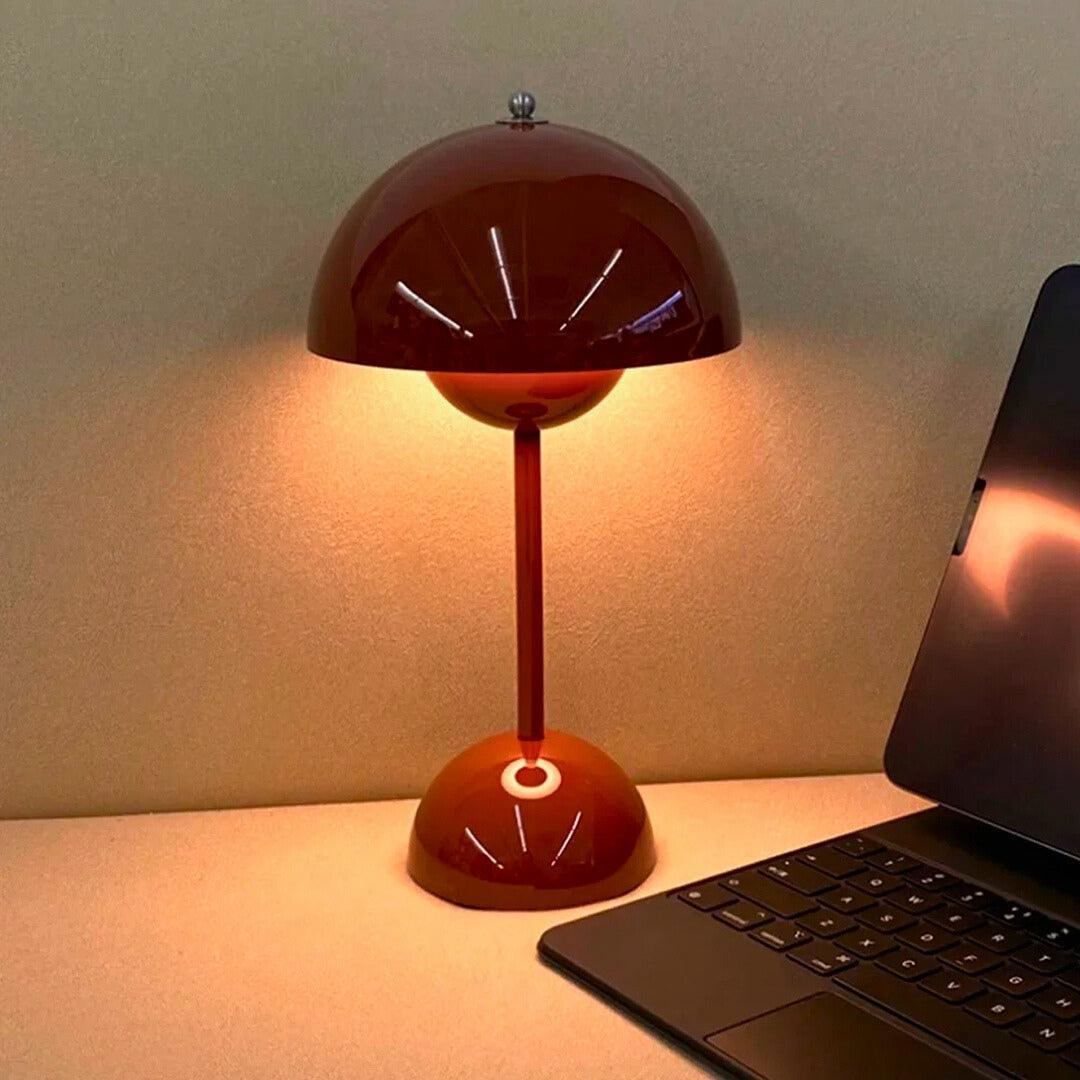 Abajur vinho aceso ao lado de um teclado, com a luz quente iluminando a parede
