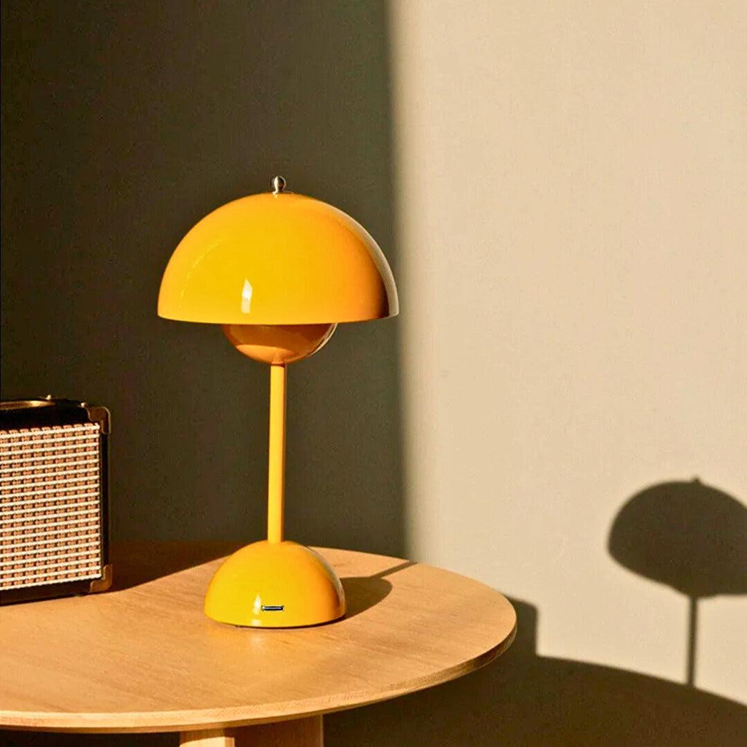 Abajur touch amarelo sem fio sobre mesa lateral de madeira, com caixa de som
