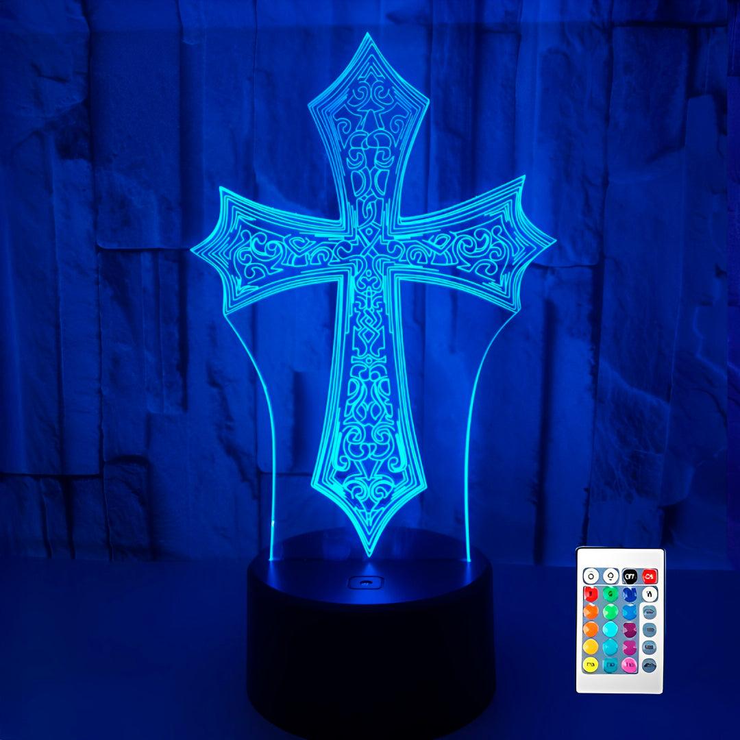 Luminária cruz gótica acesa em azul sobre fundo escuro, com o controle remoto ao lado