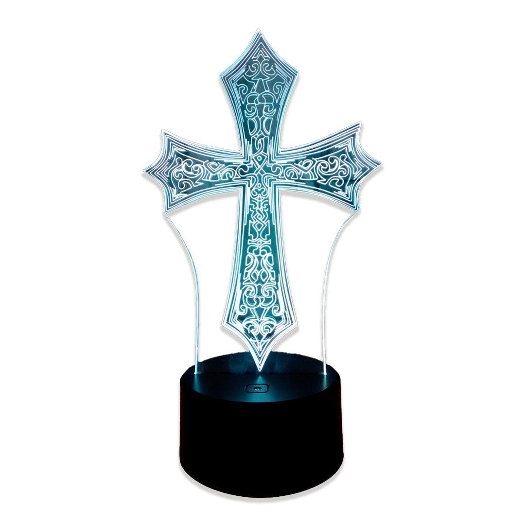 Cruz ornamentada de acrílico com arabescos gravados, acesa em azul claro sobre fundo branco