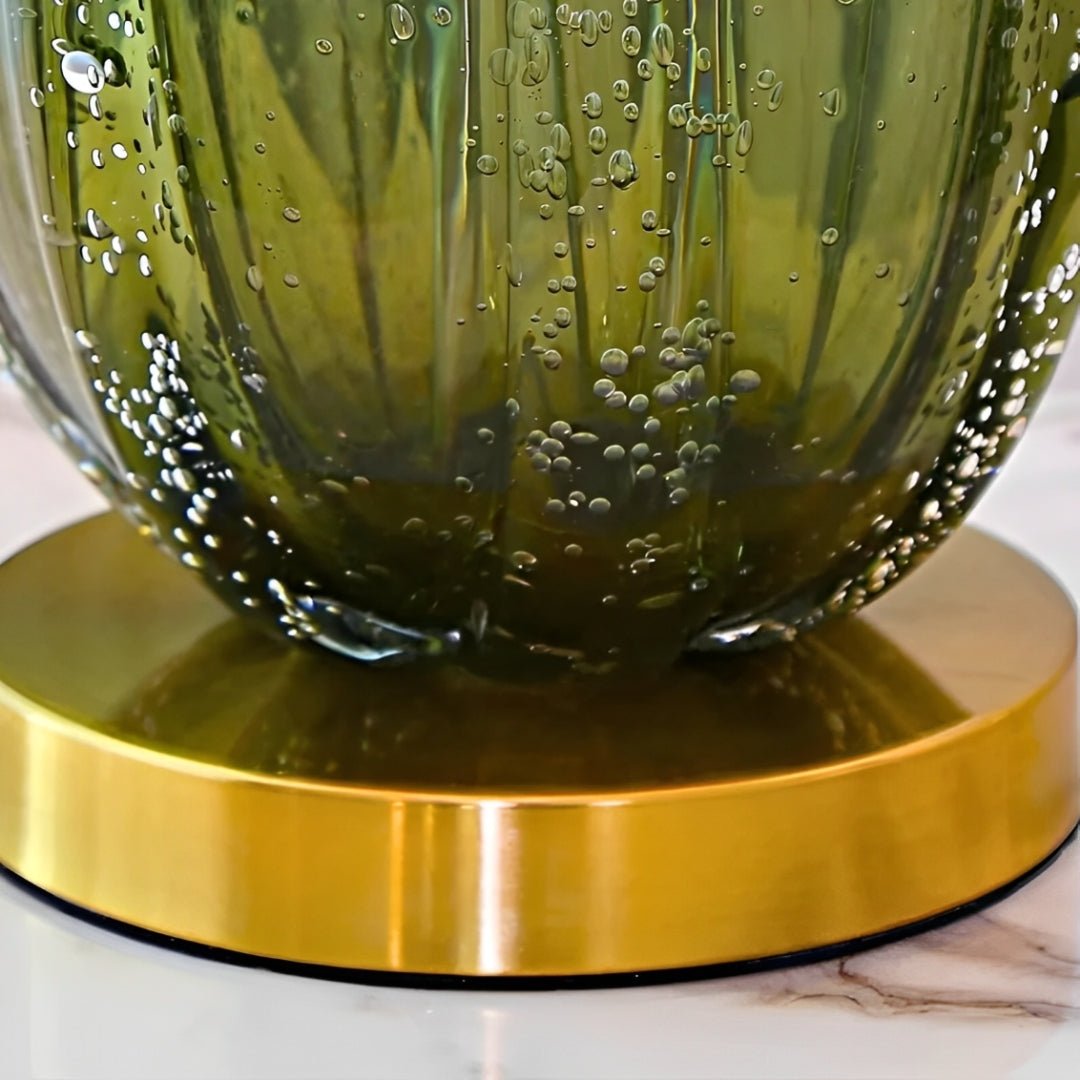 Disco de metal dourado sob a base de vidro verde com bolhas, visto de perto