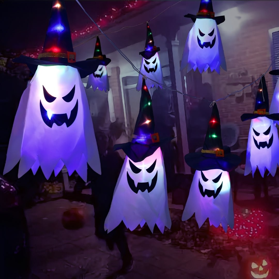 Fantasmas acesos em lilás e chapéus com LEDs coloridos pendurados num pátio à noite