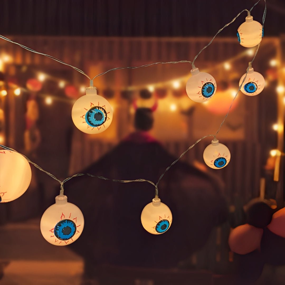 Olhos assustadores de Halloween acesos em fio fino, com luzes de festa ao fundo