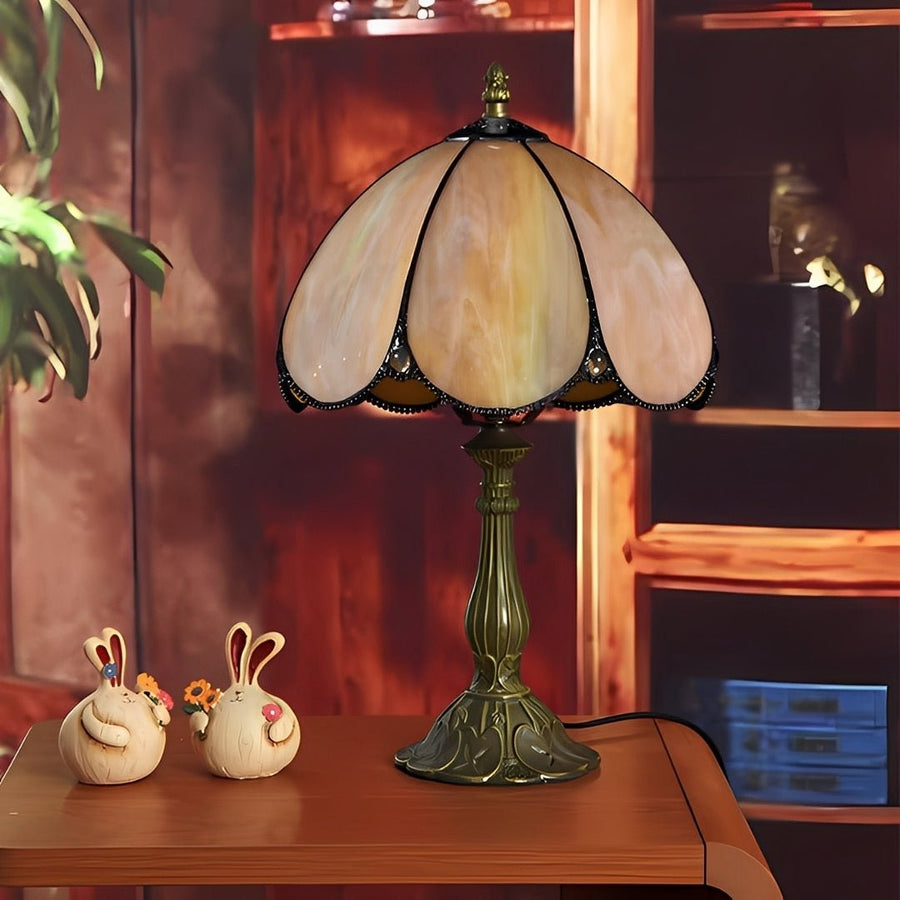 Abajur de vitral apagado sobre mesa de madeira, com dois coelhos decorativos ao lado