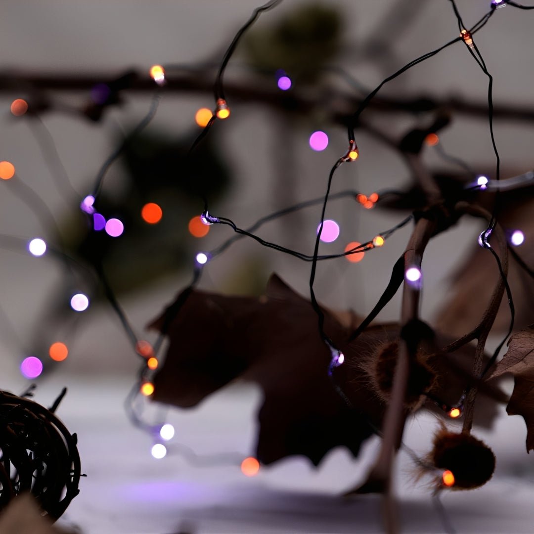 Micro LEDs laranja e roxos em fio preto fino, entre galhos secos e folhas