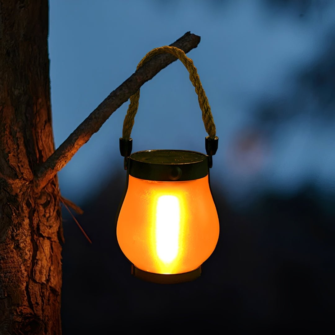 Lanterna solar decorativa acesa com efeito chama, pendurada num galho pela corda de cânhamo
