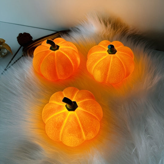 Luminária abóbora de LED, três peças acesas em laranja sobre uma manta felpuda branca