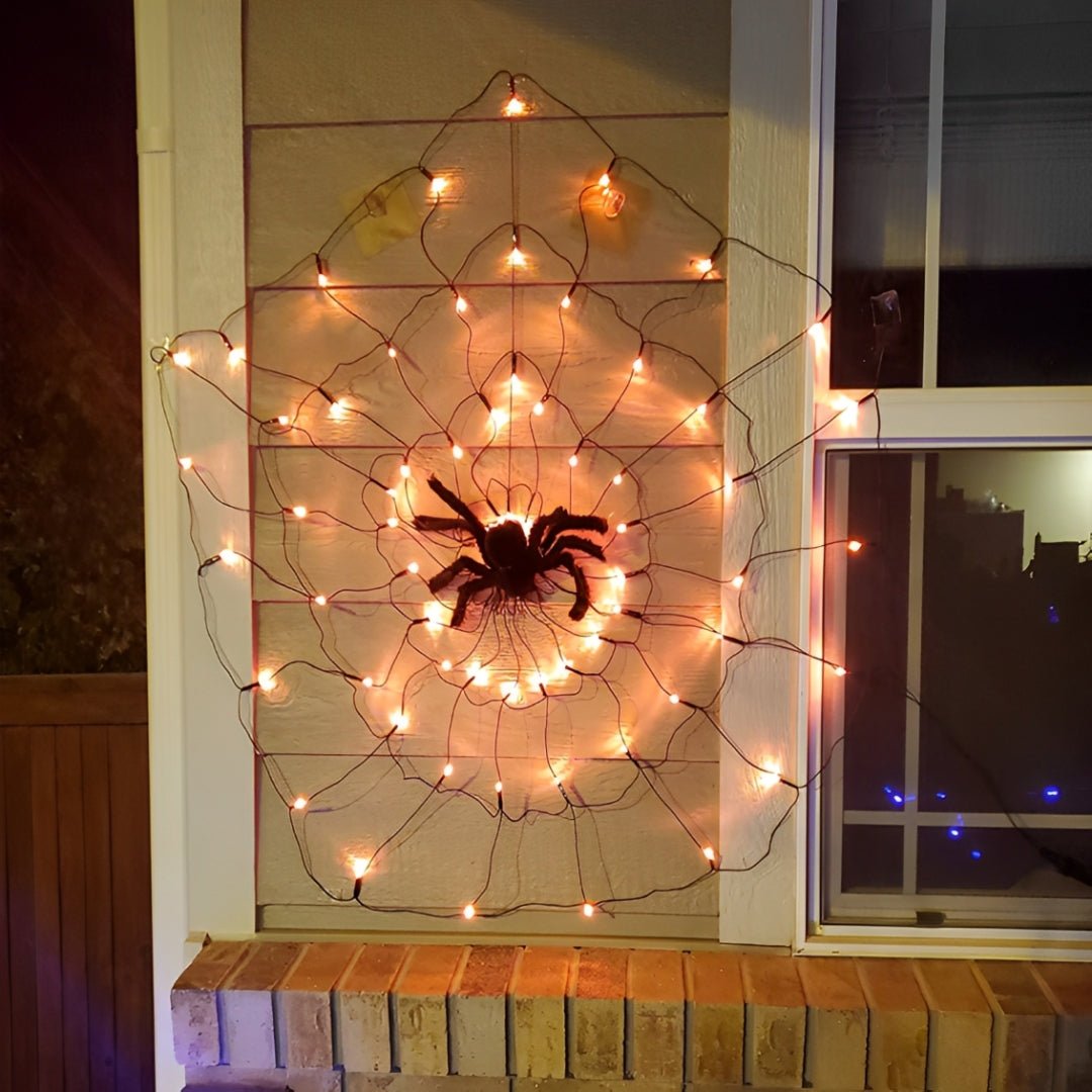 Teia laranja acesa na parede externa de uma casa, com aranha felpuda no centro