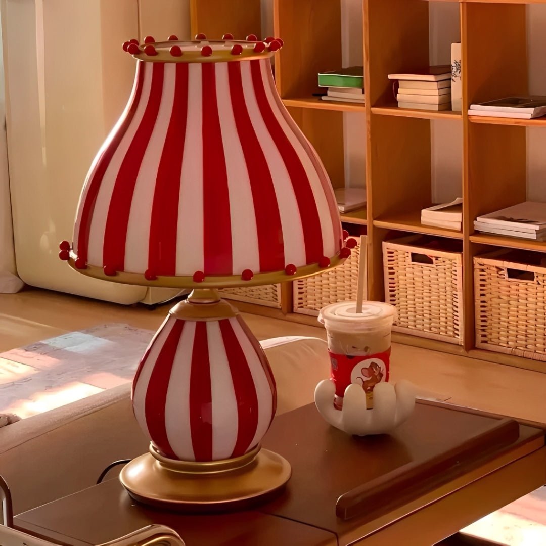 Cúpula e base listradas sobre uma mesa de madeira, com estante de livros ao fundo