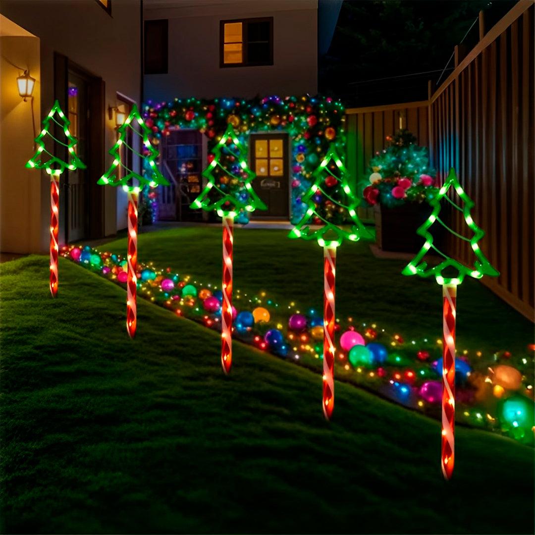 Fileira de pinheirinhos acesos em verde no gramado de uma casa decorada para o Natal