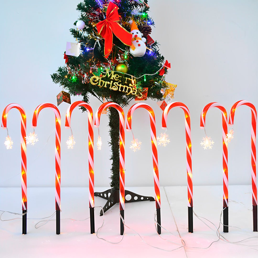 Bengalas de Natal acesas em fila diante de uma árvore de Natal enfeitada