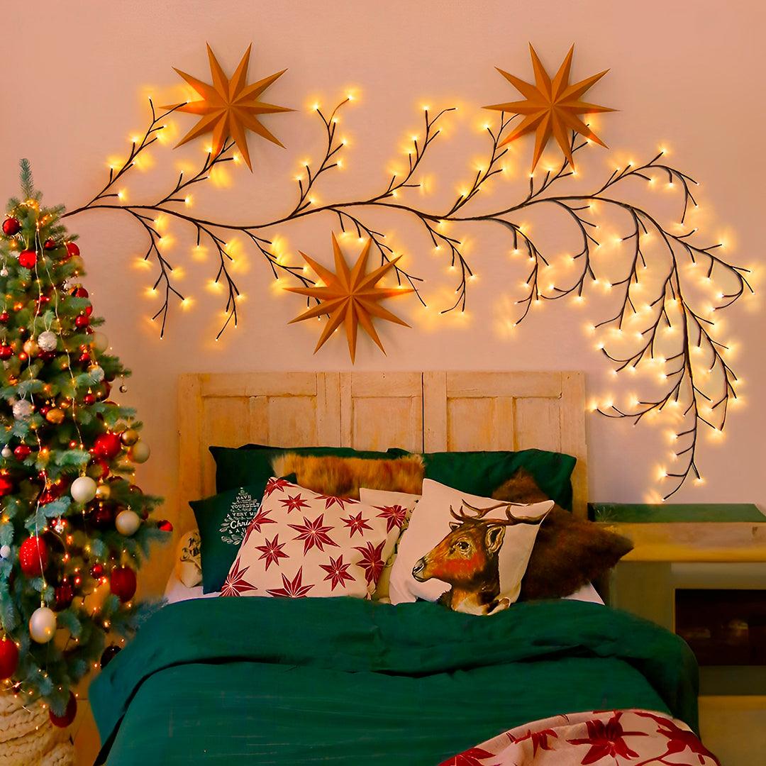 Galhos acesos sobre a cabeceira, entre estrelas decorativas e uma árvore de Natal