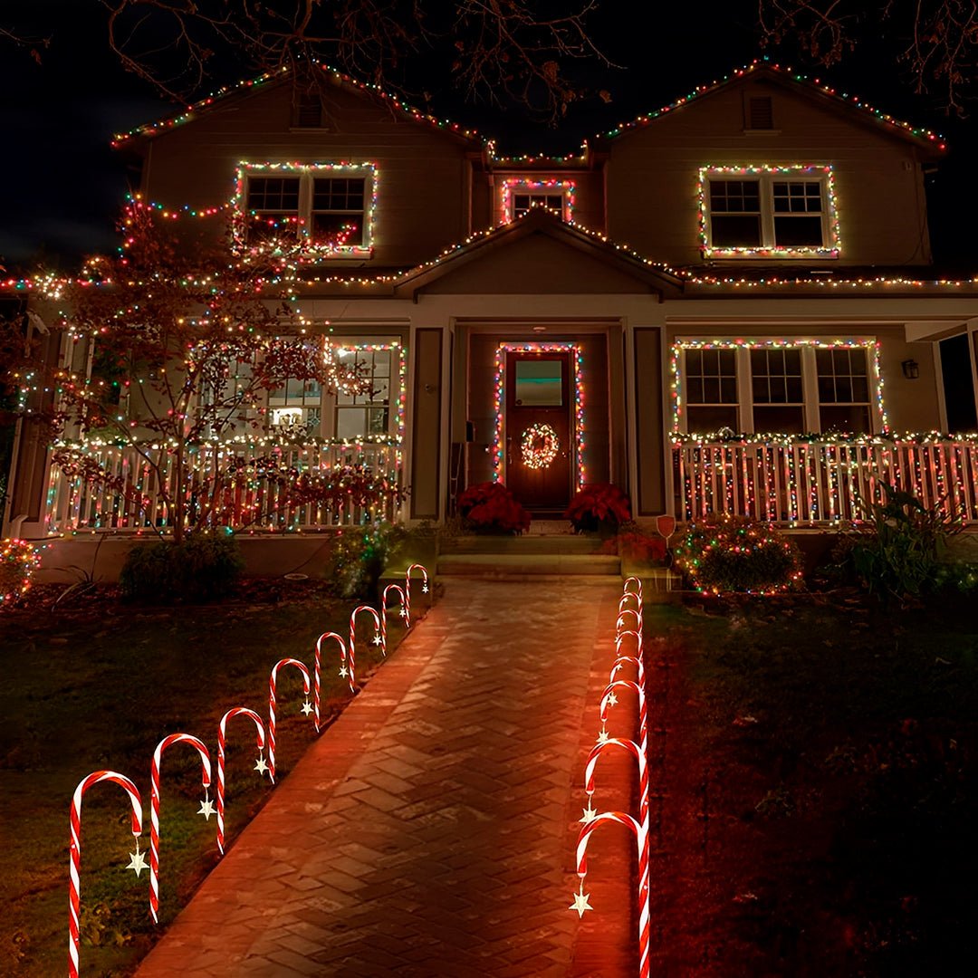 Casa decorada para o Natal, com bengalas acesas dos dois lados do caminho de tijolos