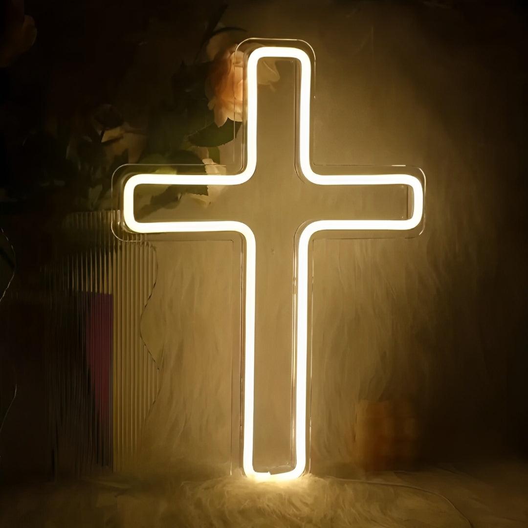 Cruz de LED neon acesa em branco quente sobre acrílico transparente, com flores ao fundo