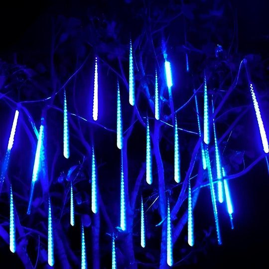 Tubos de luz azul de LED pendurados em galhos de árvore, acesos à noite
