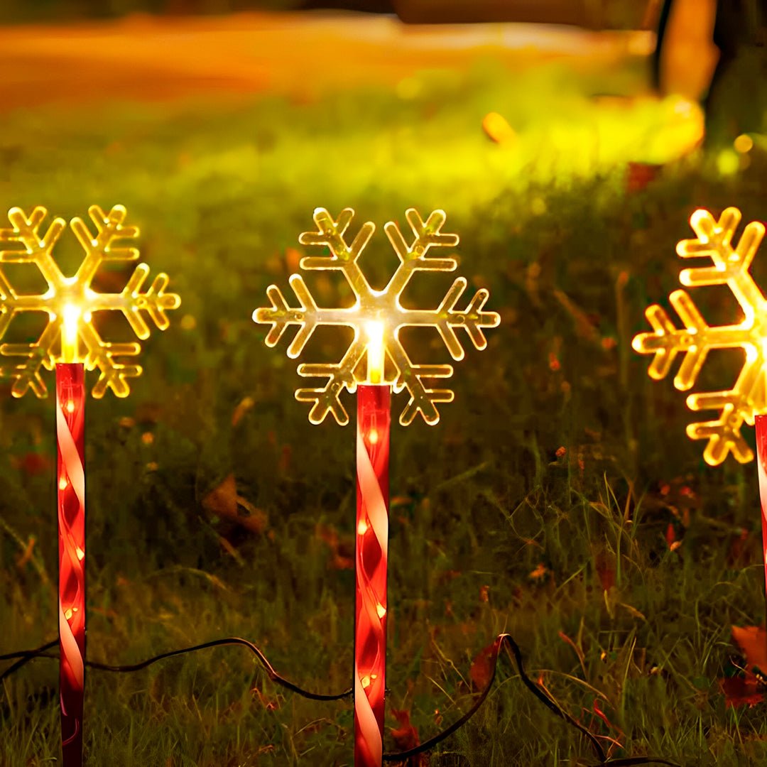 Flocos de neve acesos em luz quente sobre hastes listradas de vermelho e branco