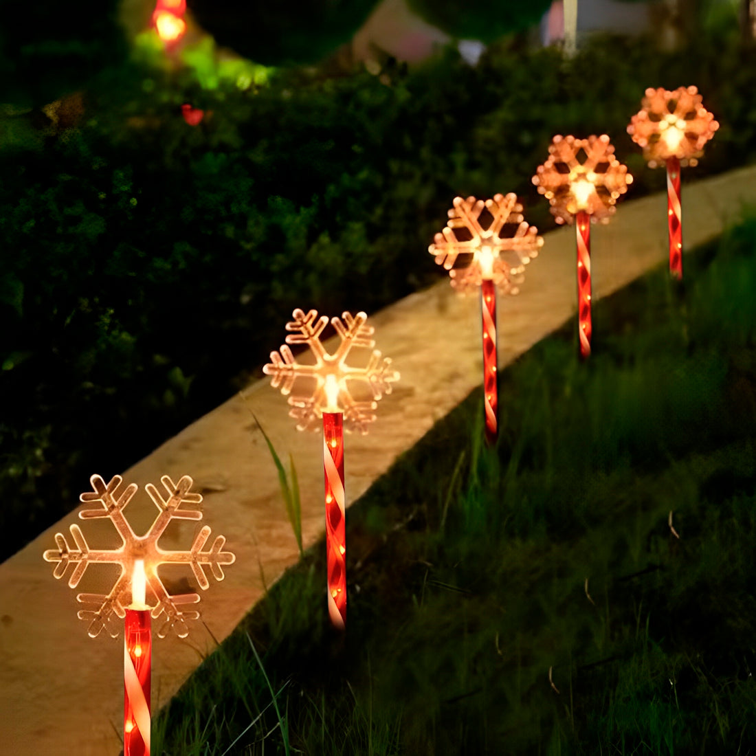 Espeto solar de Natal, modelo floco de neve, aceso em fileira junto à calçada