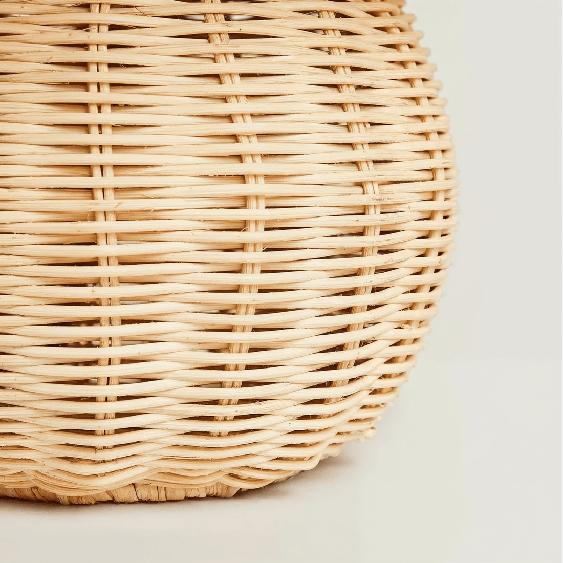 Detalhe da base esférica, com hastes finas de rattan entrelaçadas em tom claro