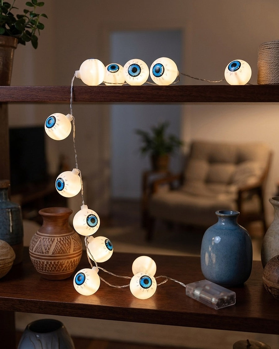Olhos de 4 cm acesos na estante, entre vasos
