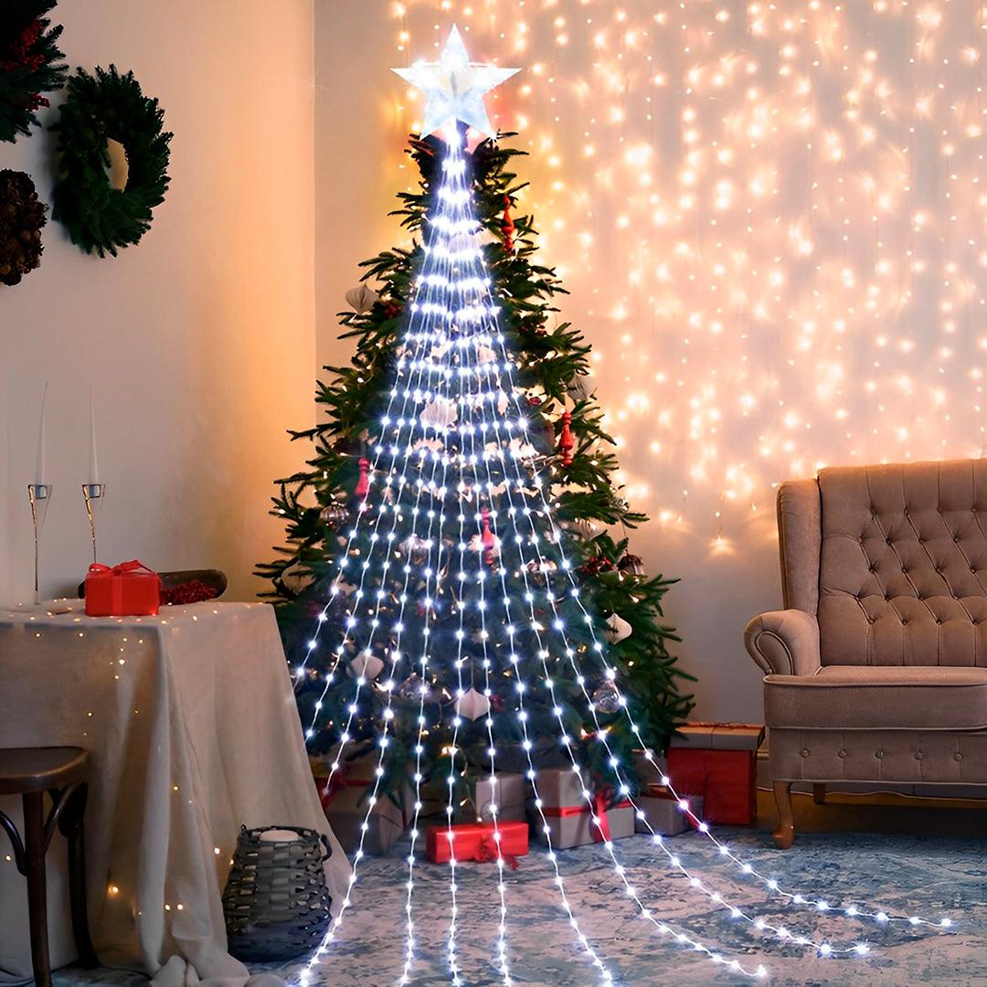 Árvore de pisca-pisca em luz branca sobre um pinheiro de Natal, em sala com poltrona