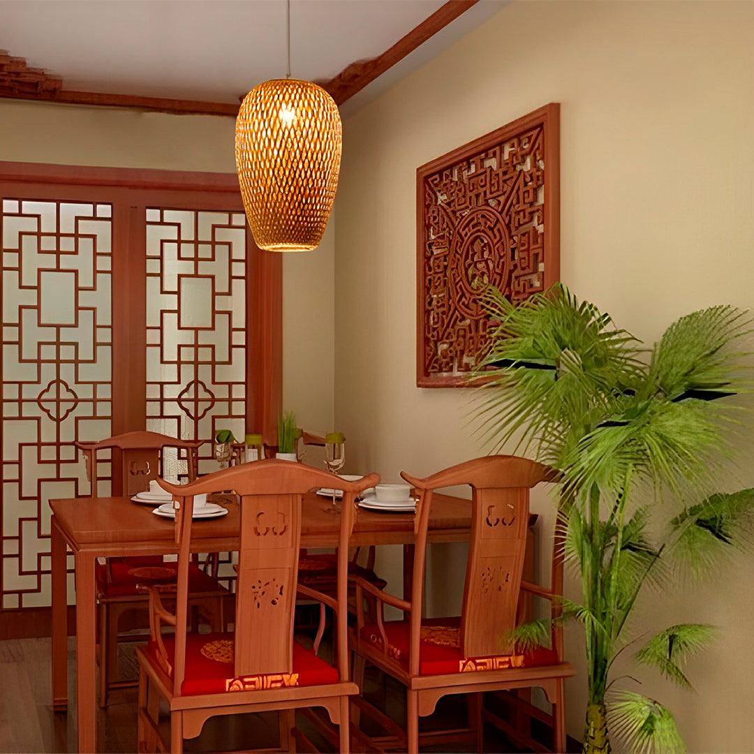Pendente de bambu aceso sobre mesa de jantar com cadeiras vermelhas e painéis de madeira