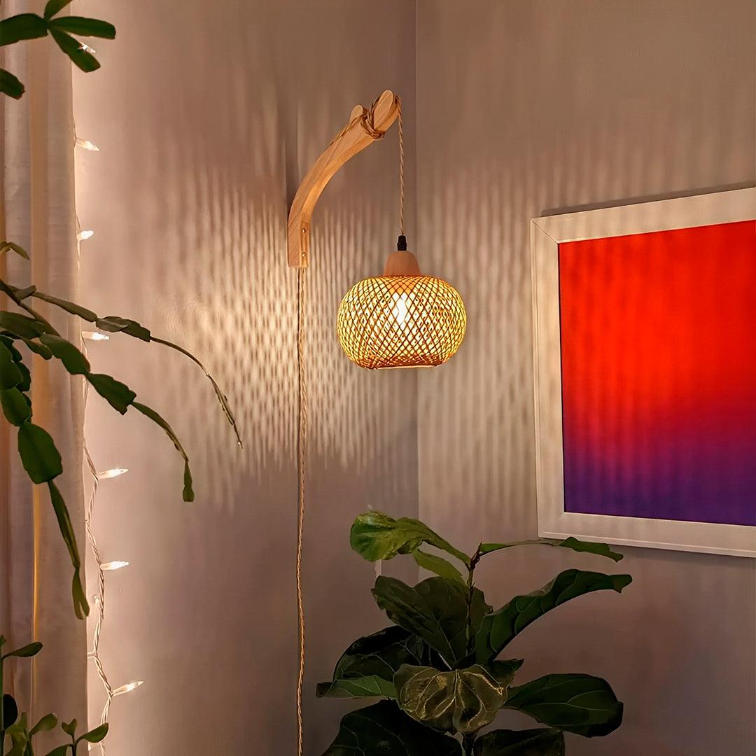 Esfera de bambu acesa num canto, com losangos de luz na parede e uma planta