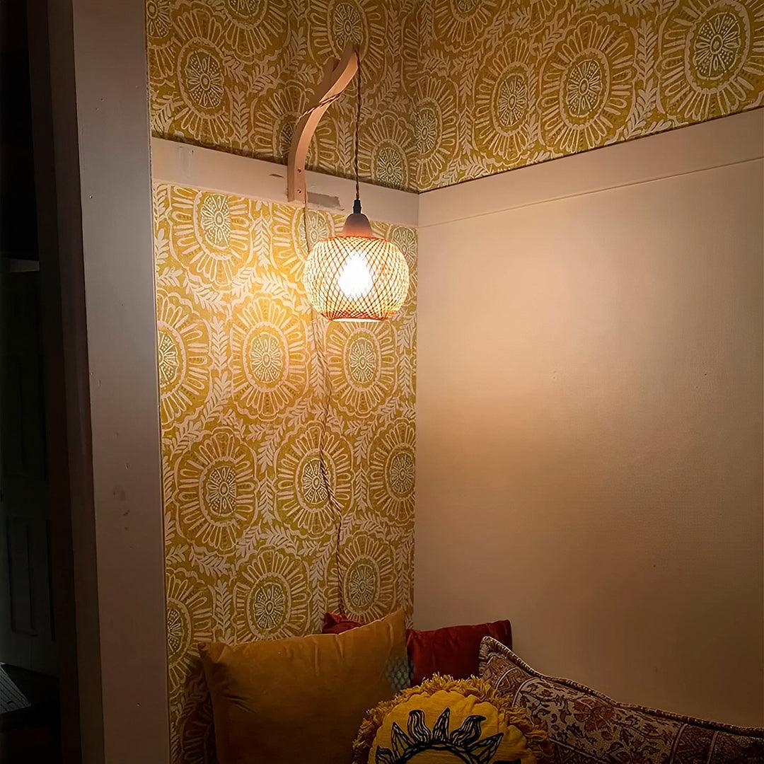 Esfera de bambu acesa num canto com papel de parede amarelo e almofadas
